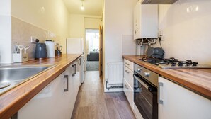 A narrow kitchen with wooden countertops, a built-in oven, and a white refrigerator. - Next to Liverpool station stadium city (Liverpool)