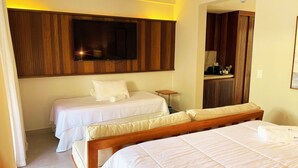 Une chambre d’hôtel avec deux lits simples, une tête de lit en bois, un téléviseur à écran plat fixé au mur et une petite table de chevet avec une lampe.