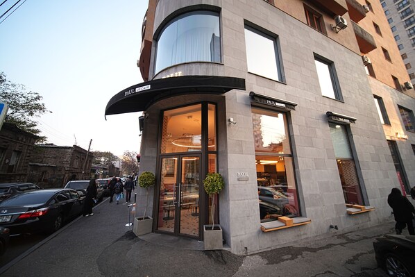 A modern building with a curved entrance, large windows, and a sign reading "PAUL CAFE". - Rooftop City View apartments (Yerevan)