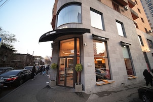 Un edificio moderno con una entrada curva, ventanas grandes y un letrero que dice "PAUL CAFE".