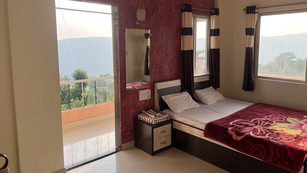 A bedroom with a bed, a nightstand, a mirror, and a window with curtains. - 2 BHK Banglow (Mahabaleswer)