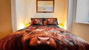 A bedroom with a large bed, floral and animal-themed bedding, a framed picture on the wall, and bedside lamps. - 1-bed Apartment Sleeps 2 -free Parking -wifi & Tv (Dundee)