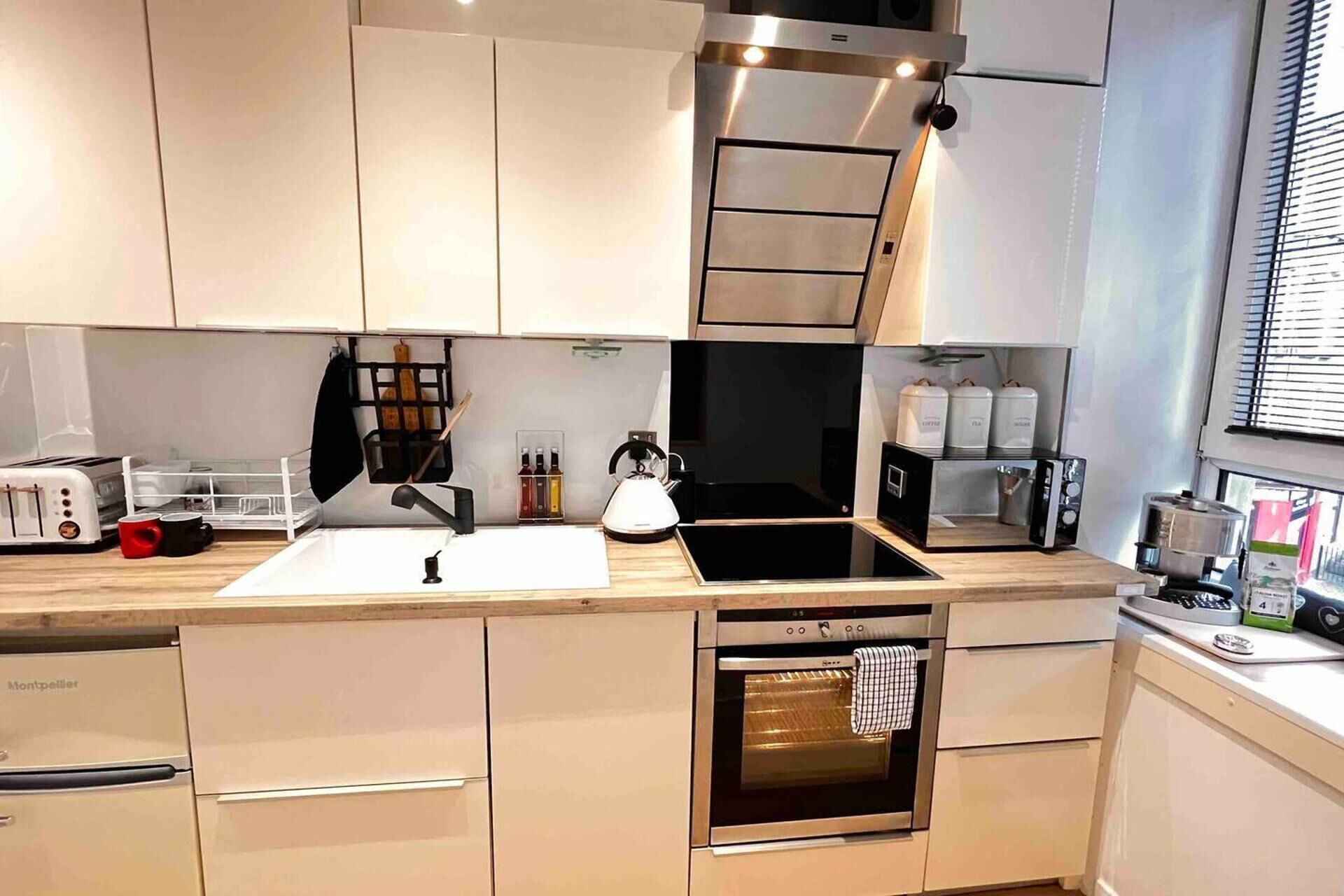 Una cocina moderna con horno empotrado, cafetera y hervidor.