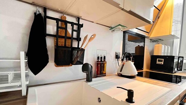 A modern kitchen with a white countertop, black kettle, and wooden utensils on the wall. - 1-bed Apartment Sleeps 2 -free Parking -wifi & Tv (Dundee)