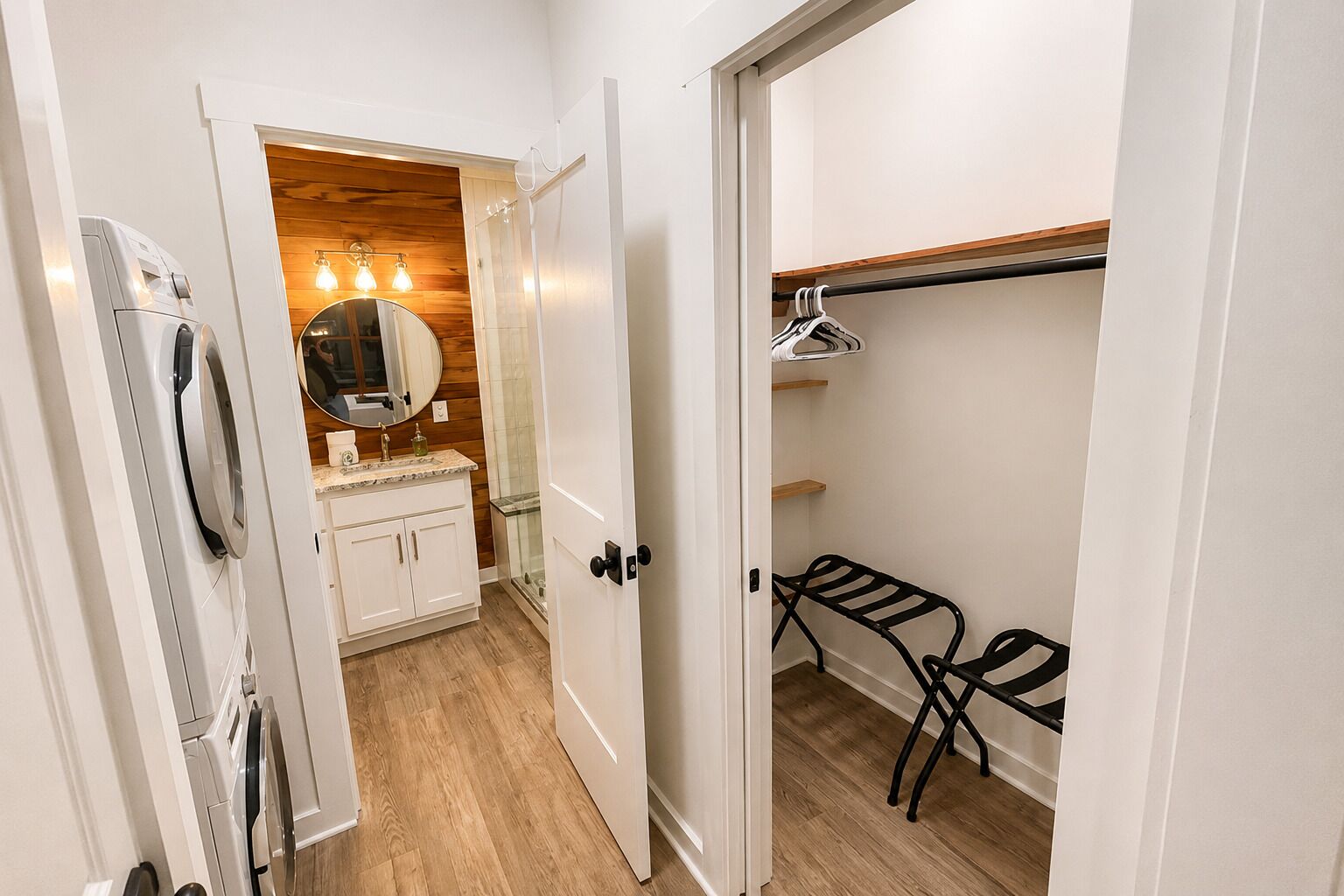 A narrow hallway with a washing machine, a mirror, and a wooden wall.