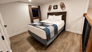 A bedroom with a bed, wooden flooring, a window with curtains, and wall decorations. - Lake Therapy at The Retreat at Water's Edge (Tracy City)