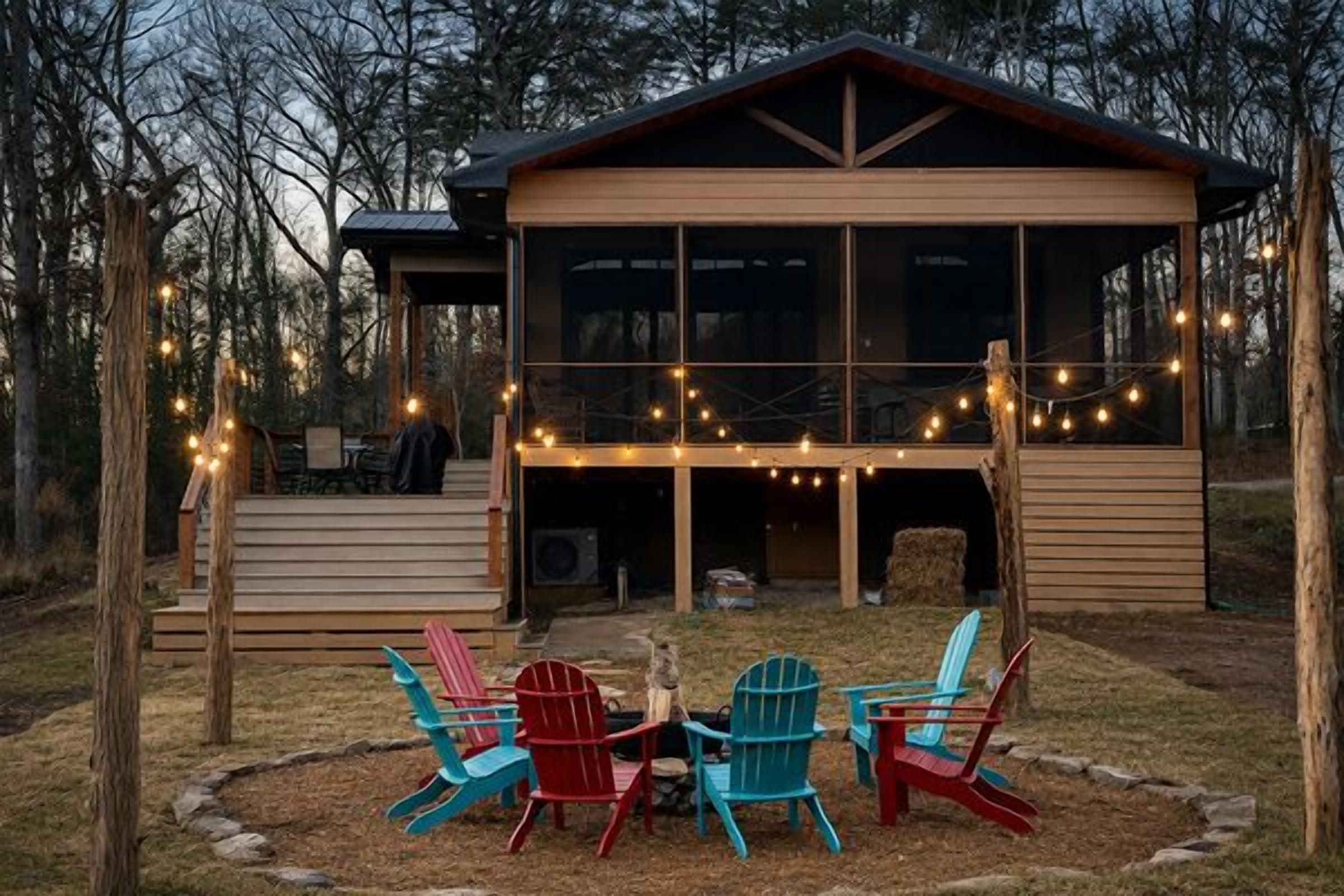 A wooden cabin with a deck, outdoor seating, and string lights.