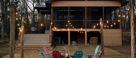 A wooden cabin with a deck, outdoor seating, and string lights.