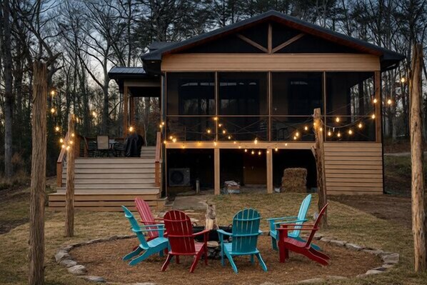 A wooden cabin with a deck, outdoor seating, and string lights.
