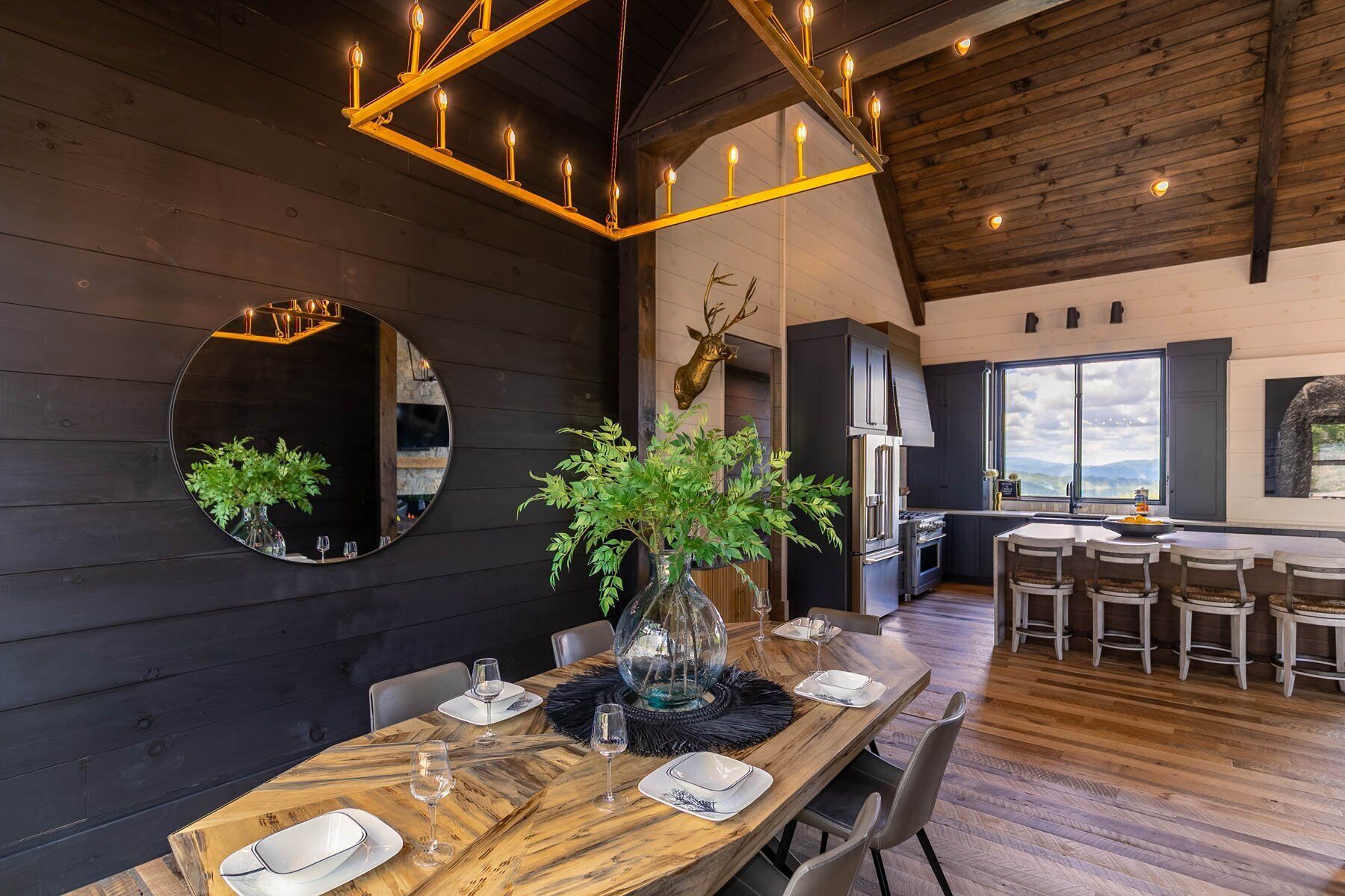 Comedor con mesa de madera dispuesta para cuatro, espejo redondo y candelabro.