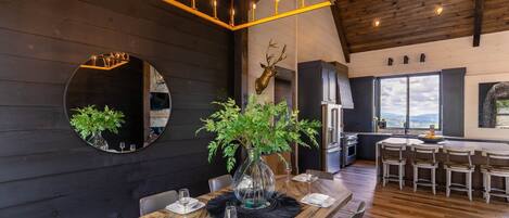 Comedor con mesa de madera dispuesta para cuatro, espejo redondo y candelabro.