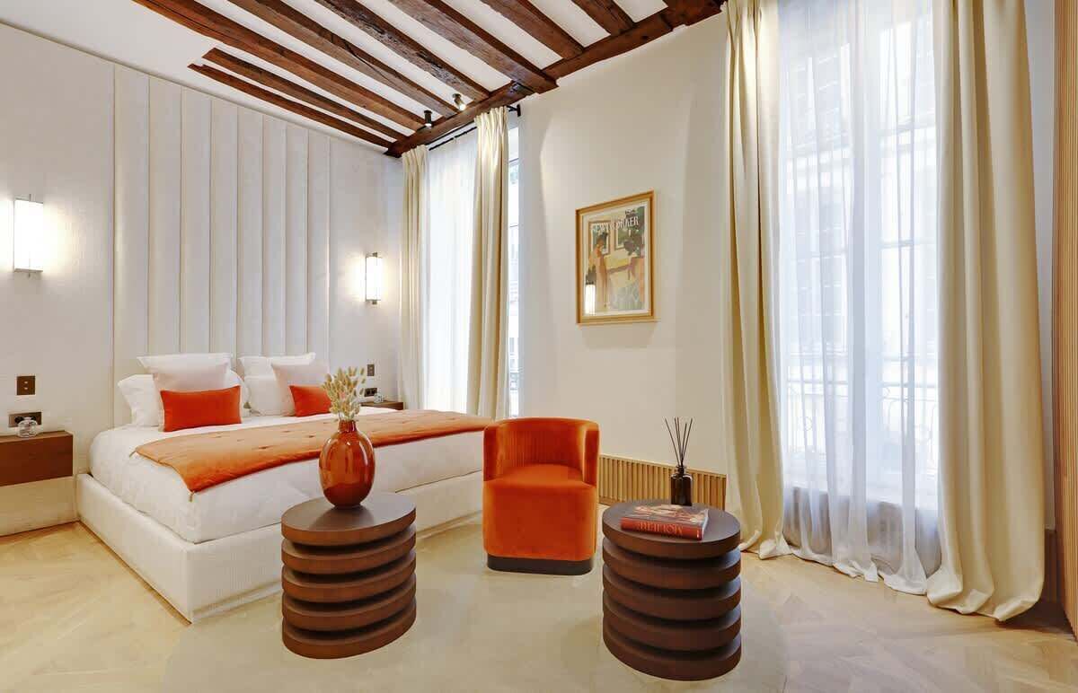 Ein modernes Schlafzimmer mit einem Bett, einem orangefarbenen Sessel und zwei Holznachttischen.