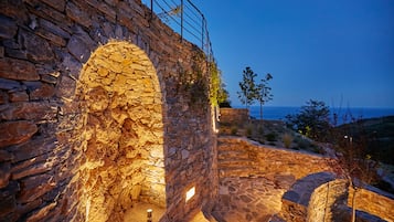 Una antigua estructura de piedra con un arco de entrada, una escalera de piedra y vistas al mar.