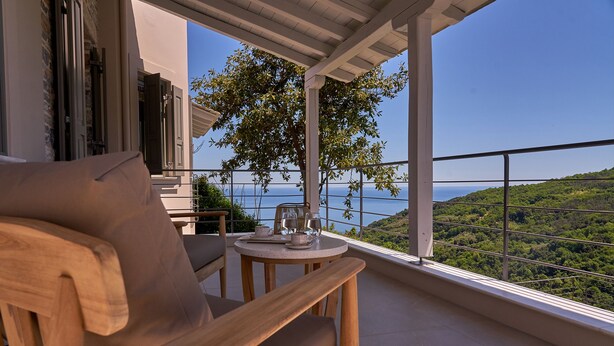 A wooden chair and table on a balcony with a view of the sea and greenery. - Sunrise Garden Hills (Zagora-Mouresi)