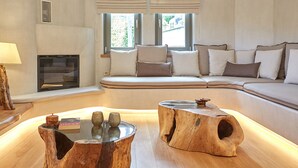 A modern living room with a wooden coffee table, a sofa with cushions, and a fireplace. - Sunrise Garden Hills (Zagora-Mouresi)