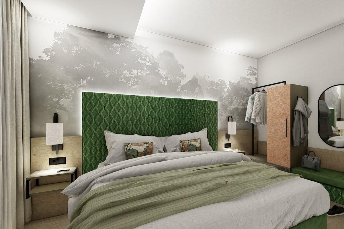 Quarto de hotel moderno com cabeceira verde, mesa de cabeceira, um banco e um espelho.