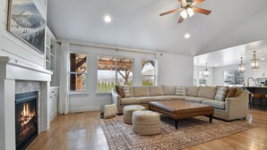 A spacious living room with a fireplace, a large sectional sofa, and a wooden floor.