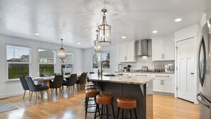 A modern kitchen with a central island, bar stools, and a dining area with chairs.