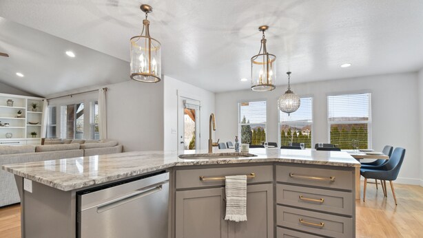 A modern kitchen with a large island, built-in appliances, pendant lighting, and a view of the outdoors.
