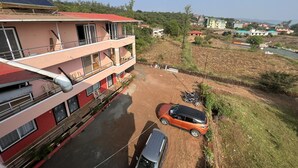Un edificio de varios pisos con balcones, un estacionamiento y vistas a un paisaje rural.