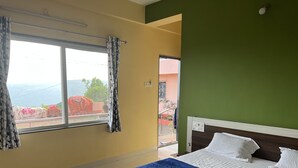 Un dormitorio con cama, una ventana con cortinas y vistas al exterior.