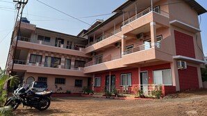Un edificio de varios pisos con balcones, unidades de aire acondicionado y una motocicleta estacionada al frente.