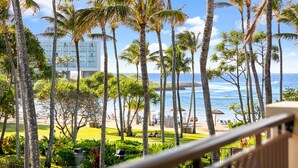 A view of a beach with palm trees and a building in the background.