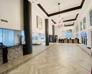 A spacious lobby with a herringbone floor pattern, a reception desk, and a large chandelier. - Shores of Panama 211~2 Bdrm/Sleeps 6 (Panama City Beach)