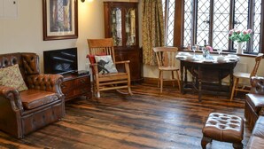 Un salon traditionnel avec un plancher en bois, des meubles en cuir et une table à manger dressée pour quatre personnes.