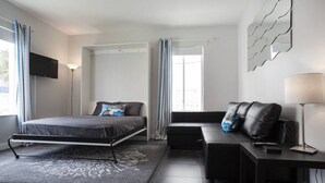 Et moderne soveværelse med seng, sofa, skrivebord og fjernsyn.