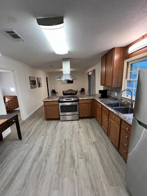 A modern kitchen with wooden cabinets, a stainless steel range, and a granite countertop.