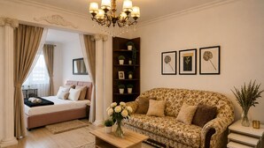 Una sala de estar con sofá, una mesa de centro, una estantería y una cama.