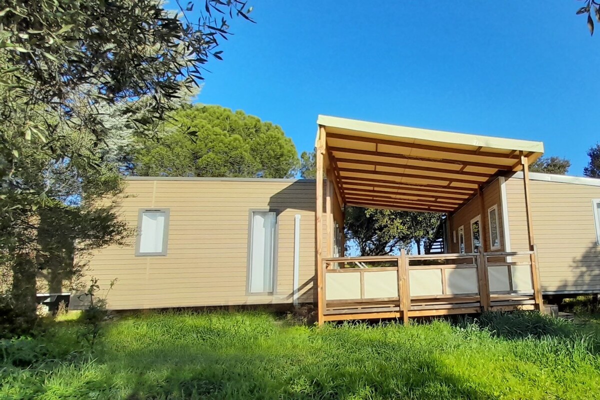 A mobile home with a wooden porch and a window.