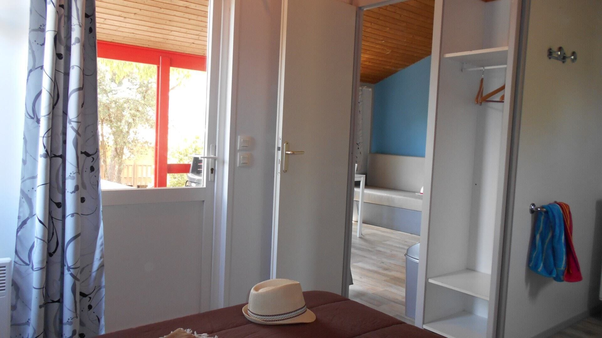 A room with a wooden ceiling, a white door, and a view of a blue wall and a white shelf with towels.