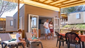 Un espace extérieur abrité, doté d’une terrasse en bois, de chaises longues et d’une table.