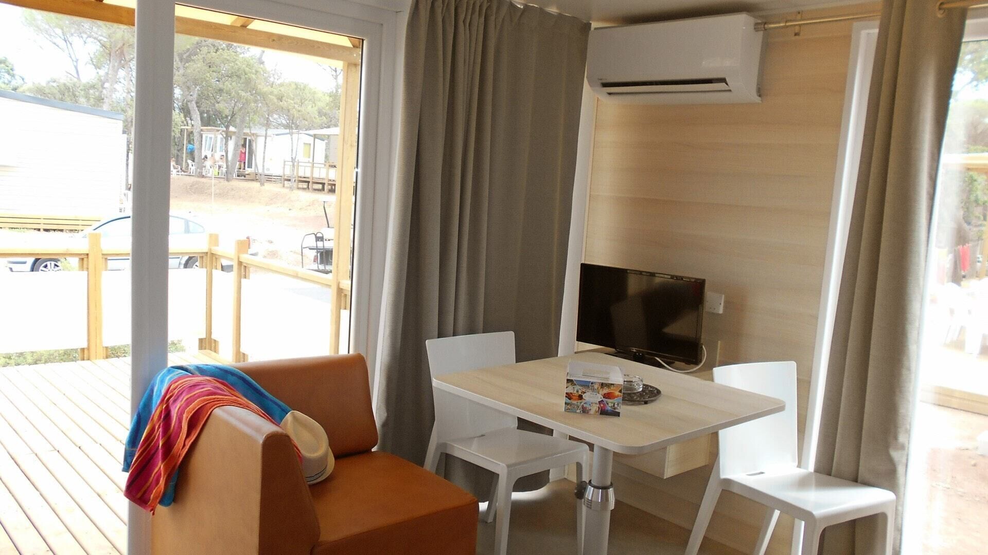 A room with a wooden deck, a sofa, a table, and a TV.