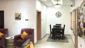 Uma sala de estar moderna com sofá, cadeiras, mesa de jantar e luminária no teto.
