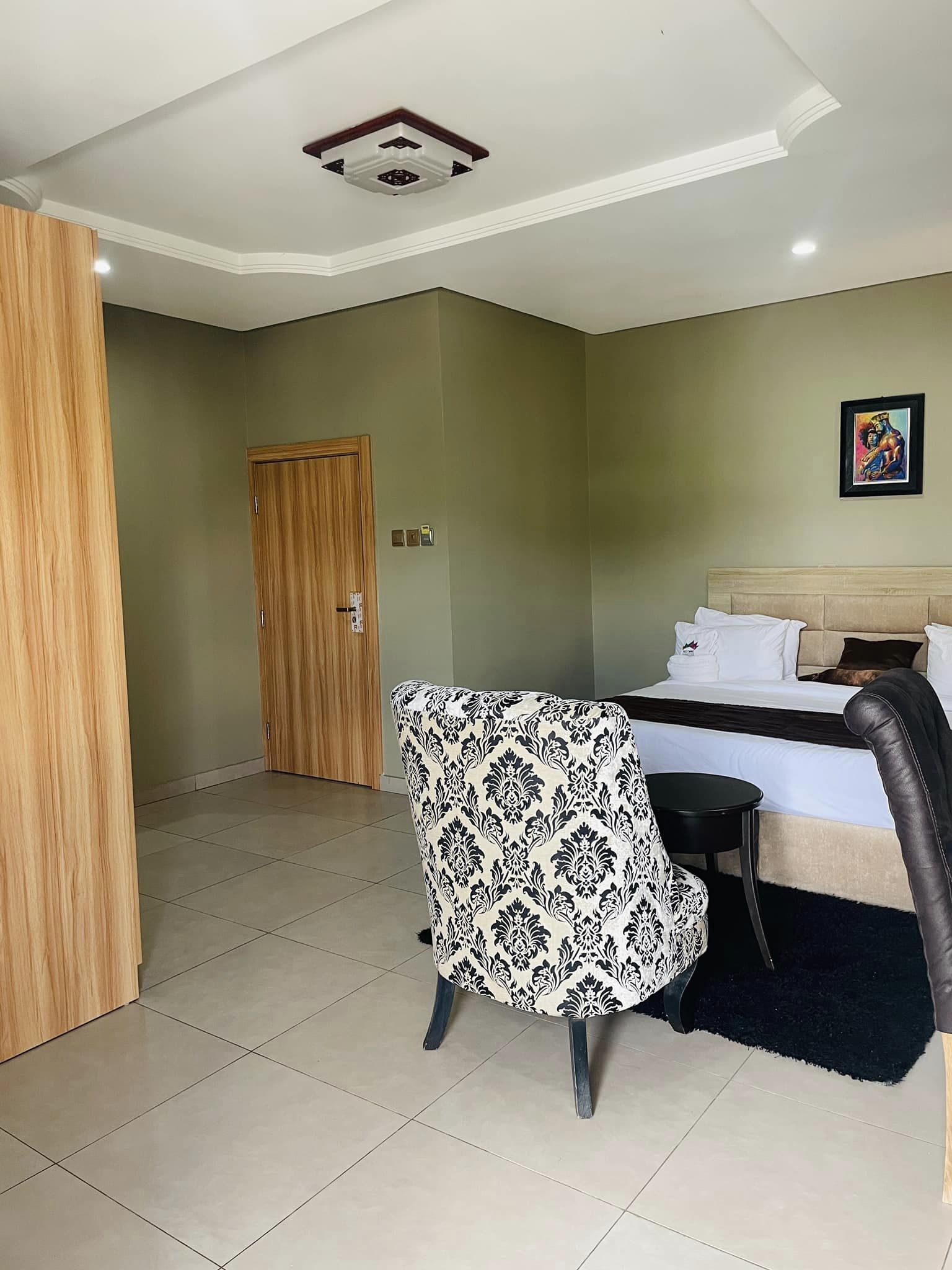 Una habitación de hotel con una cama, una silla, una mesita y una puerta.