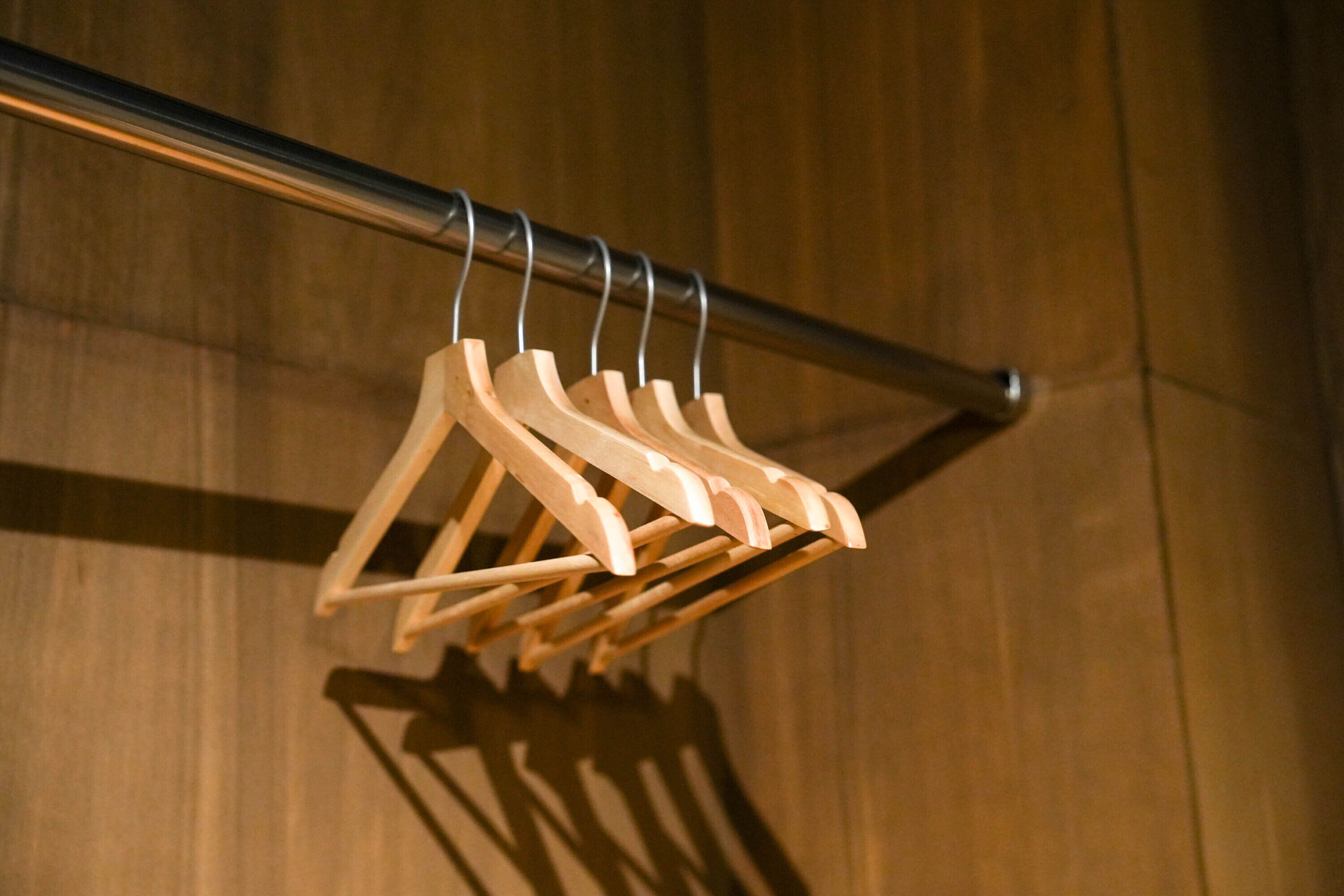 A wooden clothes rack with multiple pegs against a wooden wall.
