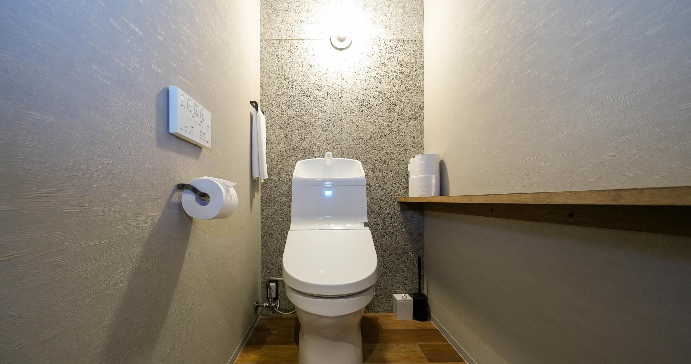A small, narrow bathroom with a toilet, a paper towel dispenser, and a hand dryer.
