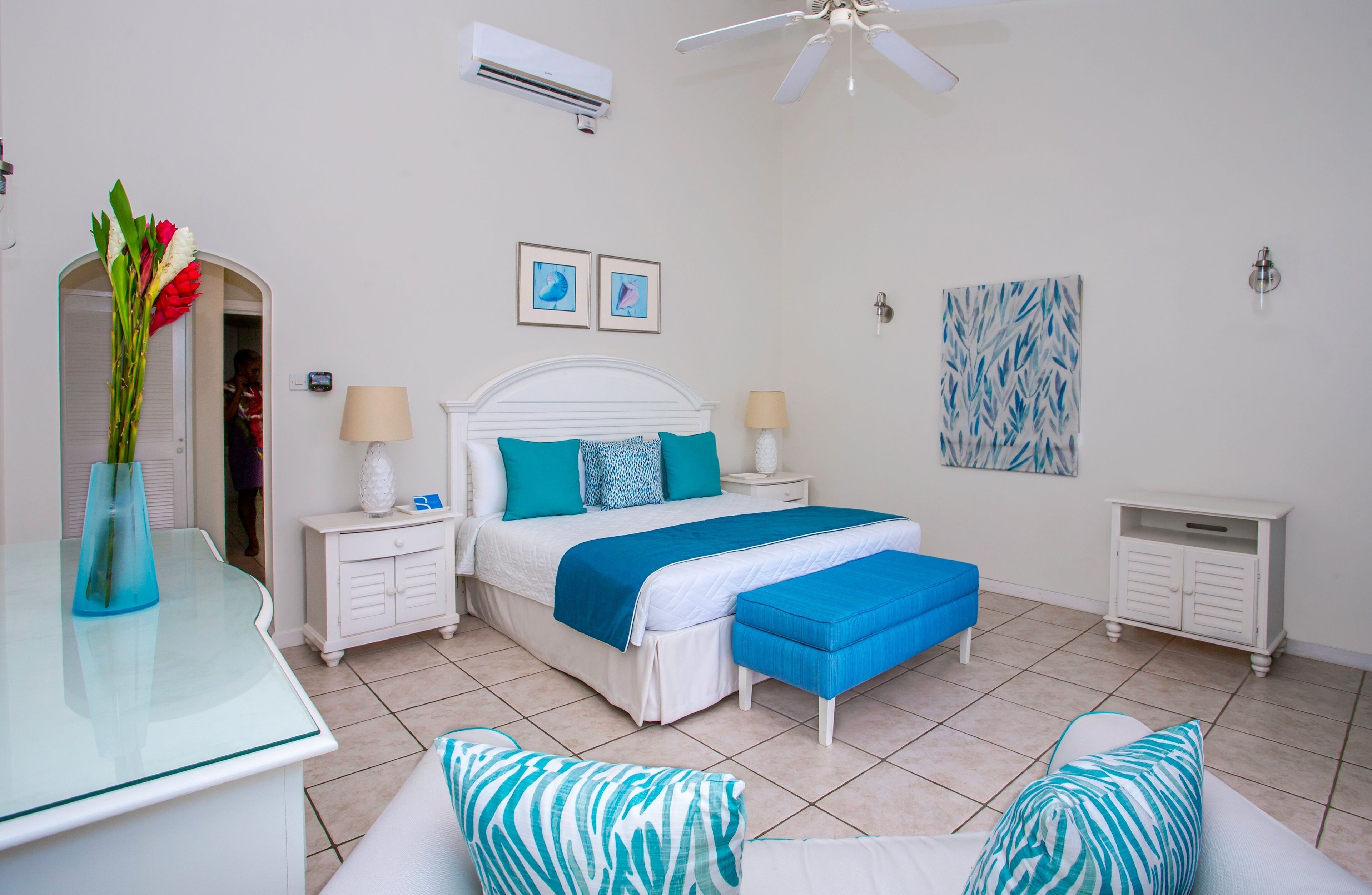 A bedroom with a bed, bedside tables, a nightstand, a desk, and a chair.