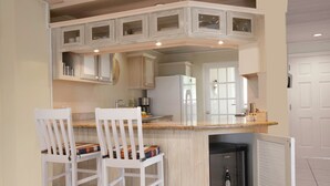 A kitchen with white cabinetry, a built-in island with bar stools, and a refrigerator. - The Harbour #6 - 3 Bedrooms in Rodney Bay 3 Townhouse by RedAwning (Gros Islet)