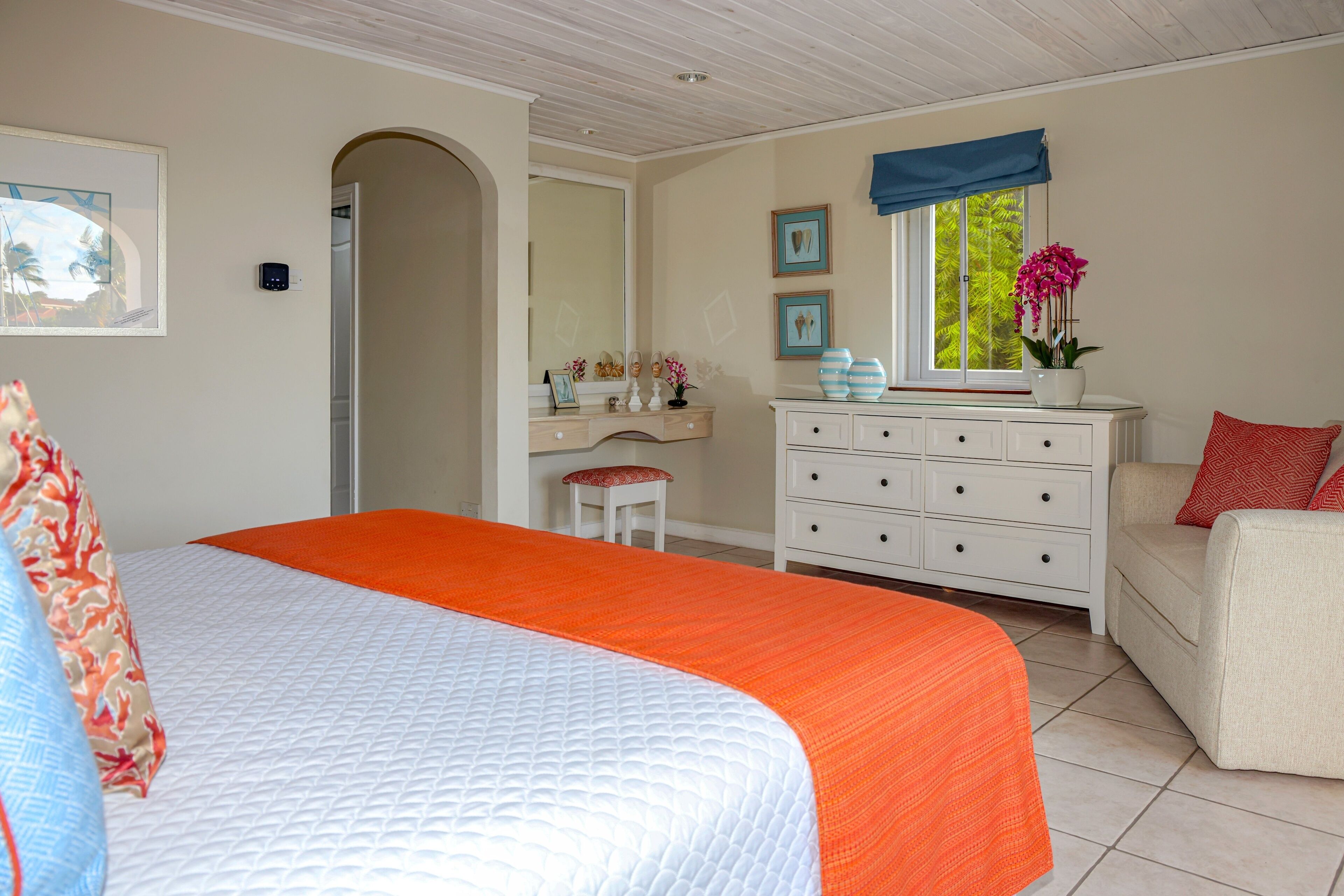 Une chambre à coucher avec un grand lit, une commode, une coiffeuse et une fenêtre avec des rideaux.