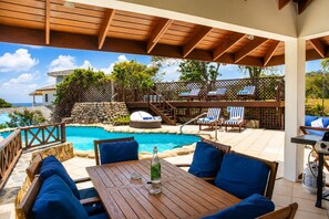 A covered outdoor area with a pool, lounge chairs, and a table with a bottle. - Hilltop 1-bed Villa With Great Views Out To Sea - Villa Cadasse 1 Bedroom Villa by RedAwning (Gros Islet)