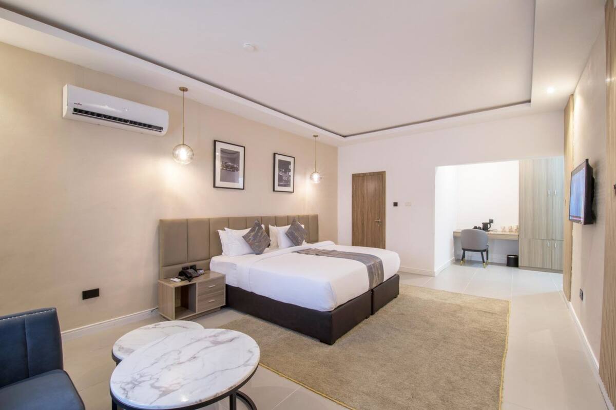 A modern hotel room with a large bed, bedside tables, a desk, and a TV.