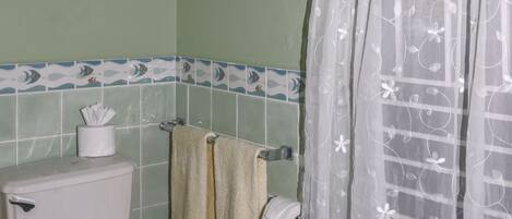A bathroom with a toilet, a towel rack, a shower curtain, and a trash bin.