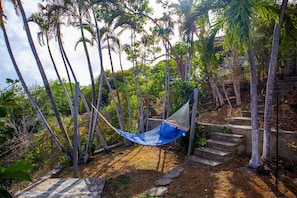 A hammock in a natural setting with trees and a stone staircase.