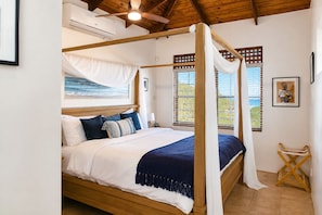 A four-poster bed with a canopy, a painting of the ocean on the wall, and a wooden ceiling. - Charming Cottage Located In Cap Estate - Orchid Cottage 1 Bedroom Home by RedAwning (Gros Islet)