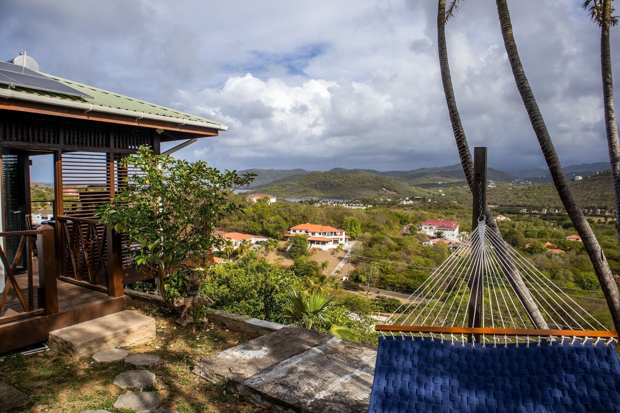 A hammock overlooking a mountainous landscape with a view of houses and greenery.