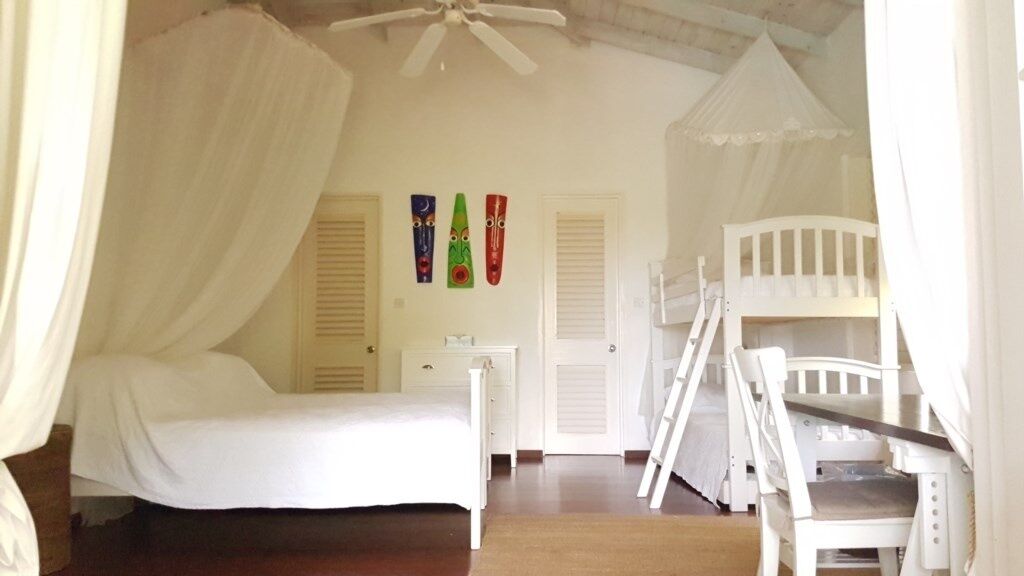 Un dormitorio con cama a dosel, literas y un escritorio.